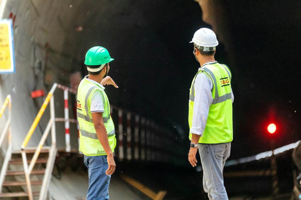 Two construction workers examine a tunnel entrance, highlighting safety and teamwork in infrastructure projects.