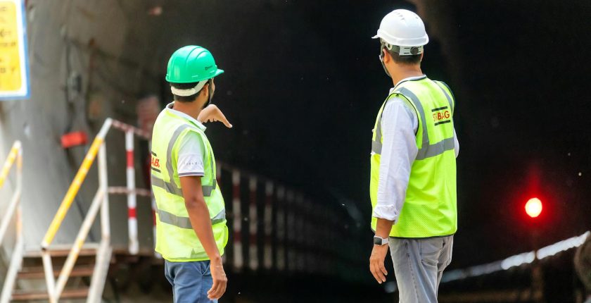 Two construction workers examine a tunnel entrance, highlighting safety and teamwork in infrastructure projects.