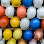 Vibrant collection of industrial safety helmets neatly arranged on a wall.