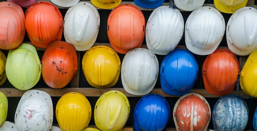 Vibrant collection of industrial safety helmets neatly arranged on a wall.