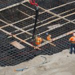 High angle view of construction workers reinforcing a steel foundation at a building site.