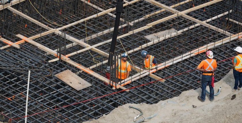 High angle view of construction workers reinforcing a steel foundation at a building site.