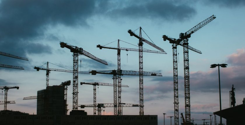 Multiple construction cranes silhouetted against the evening sky, capturing industrial progress.