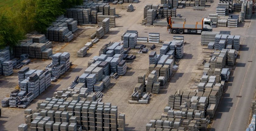 Aerial shot of a vast industrial yard with stacked bricks and a loading truck, captured on a clear day.