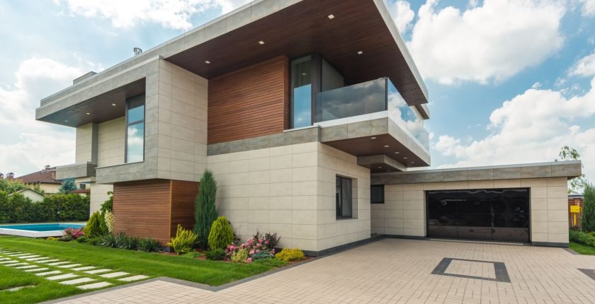 Contemporary luxury house with a sleek design, lush garden, and blue sky.